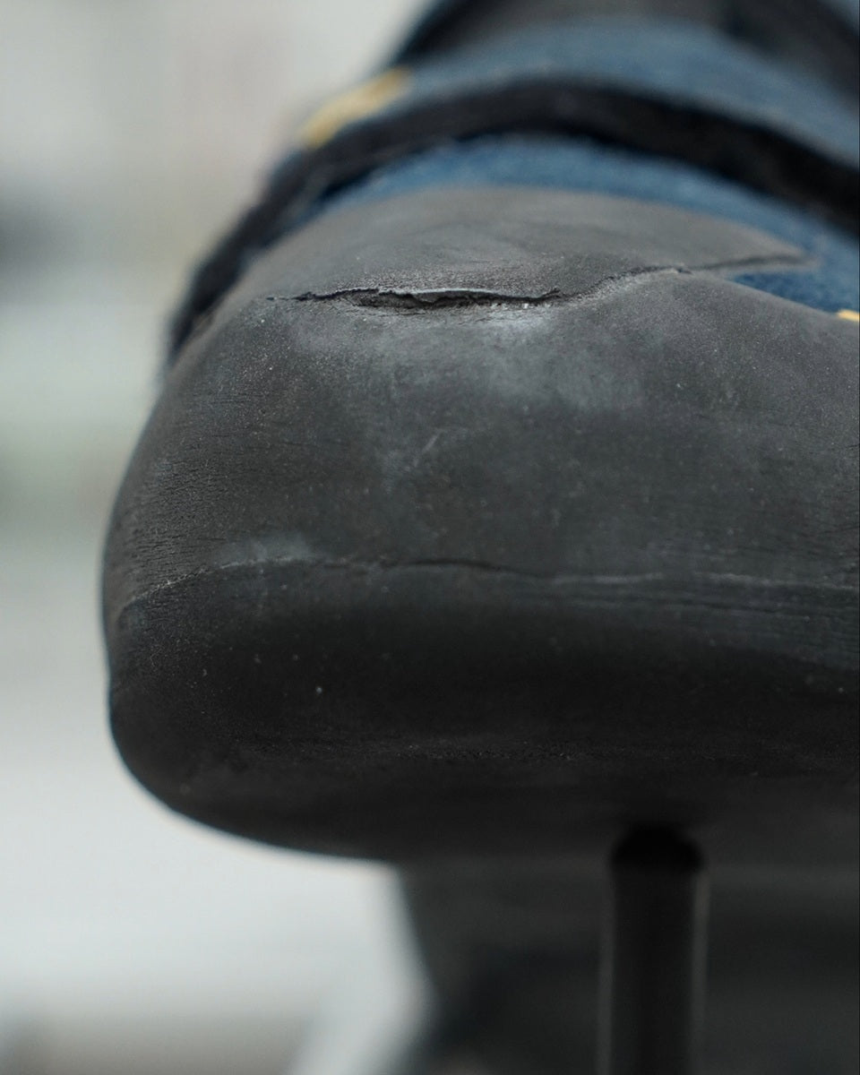 Close-up of a worn-out black shoe sole with visible cracks.