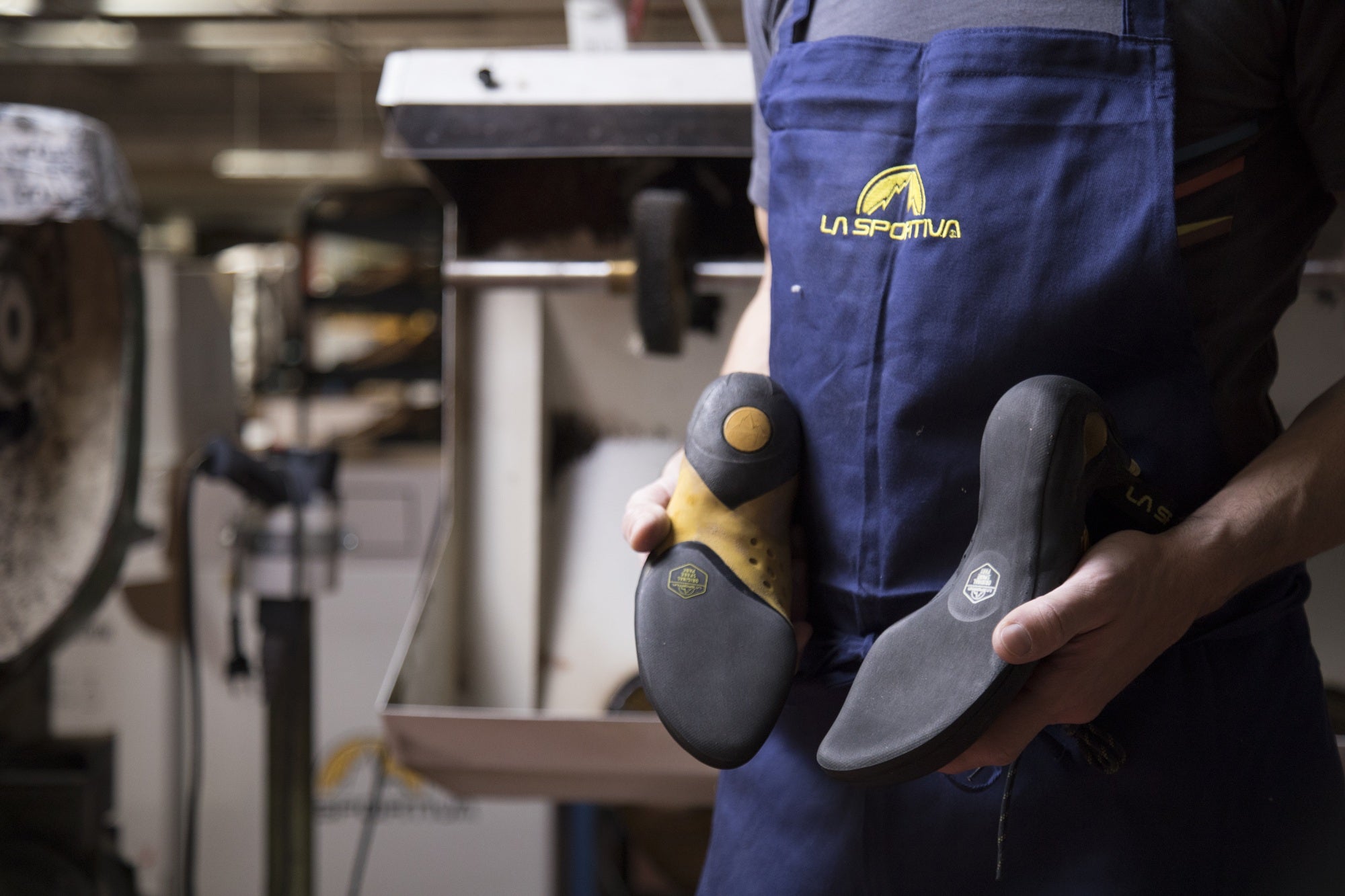 Person holding climbing shoes with La Sportiva branding in a workshop setting
