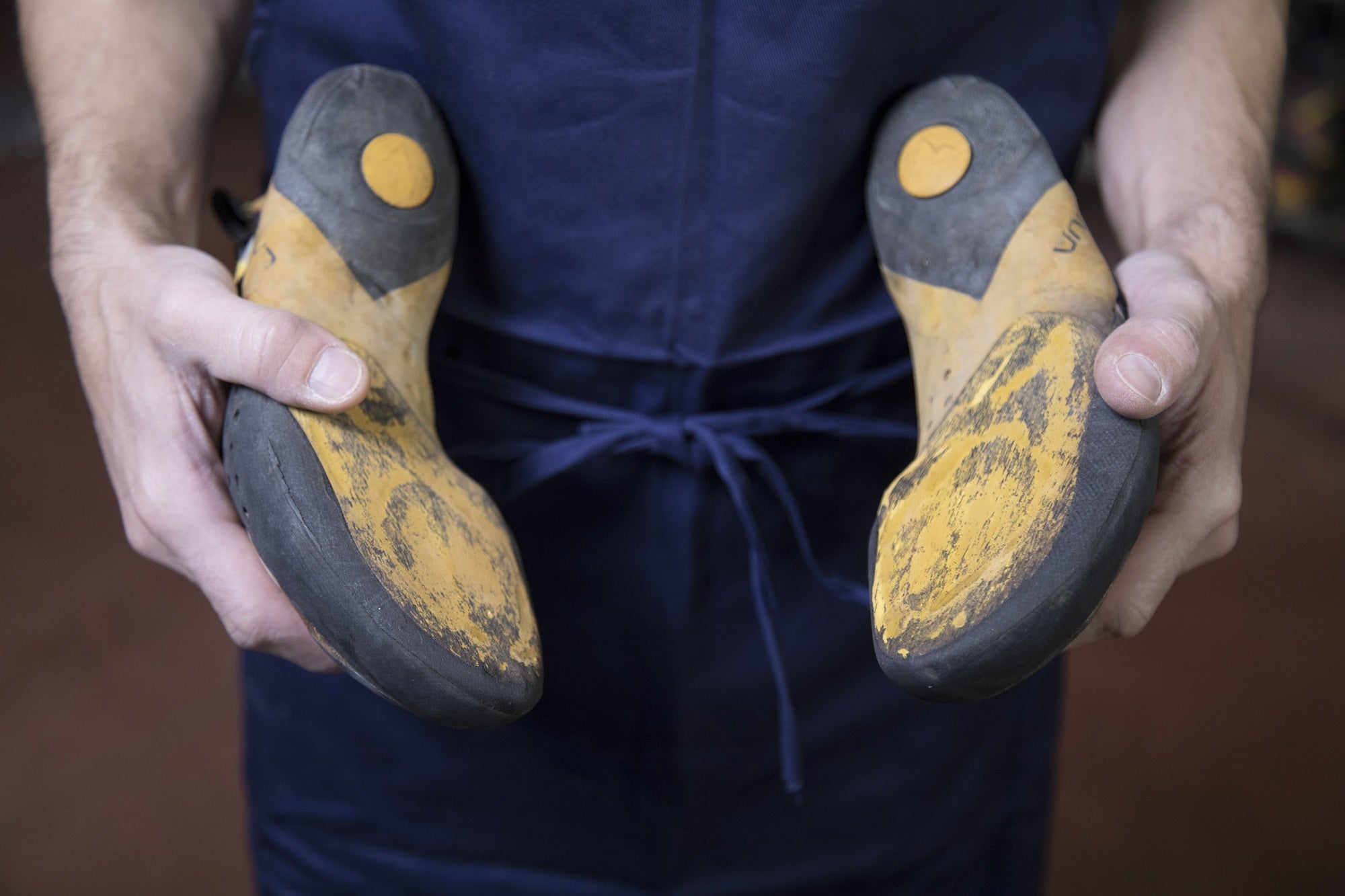 Person holding a pair of yellow and black climbing shoes.
